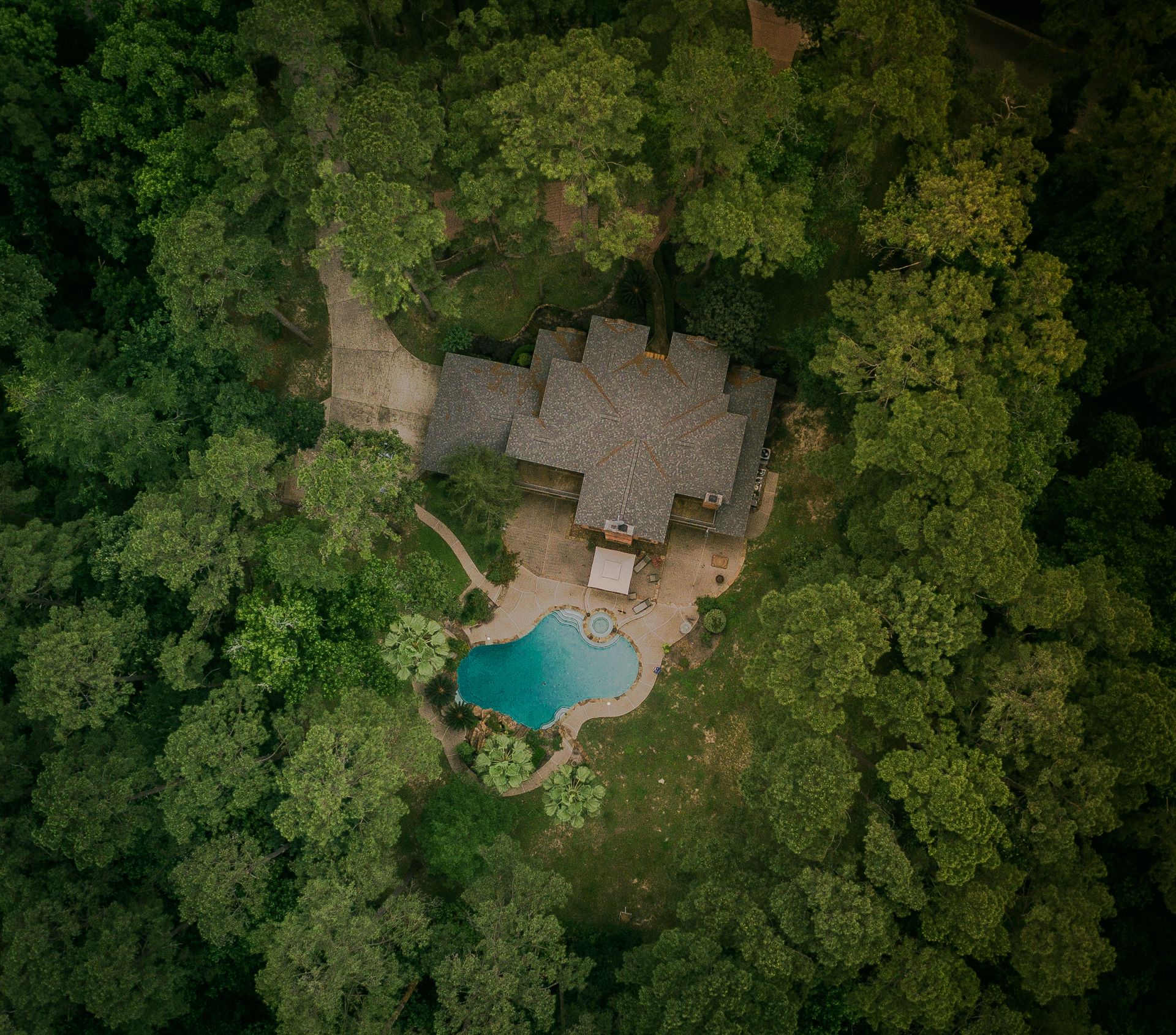 Aerial view of house with pool surrounded by trees